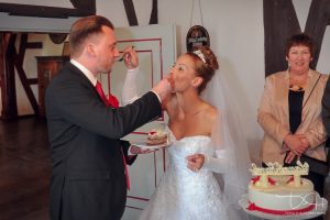 Das Brautpaar füttert sich mit dem ersten Kuchenstück gegenseitig - Fotograf Hochzeit