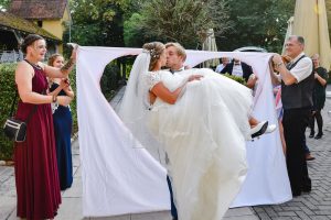 Bräutigam trägt Braut durch ein ausgeschnittenes Herz